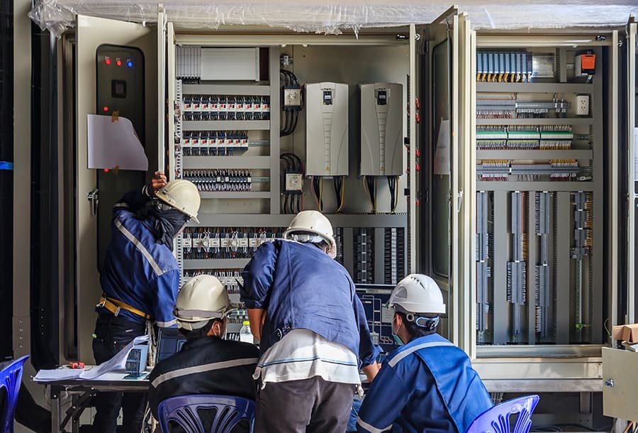 engineers working and checking plc cabinet wiring