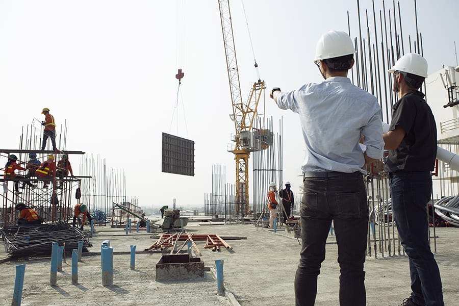 Two engineers work on the construction site. They are checking t